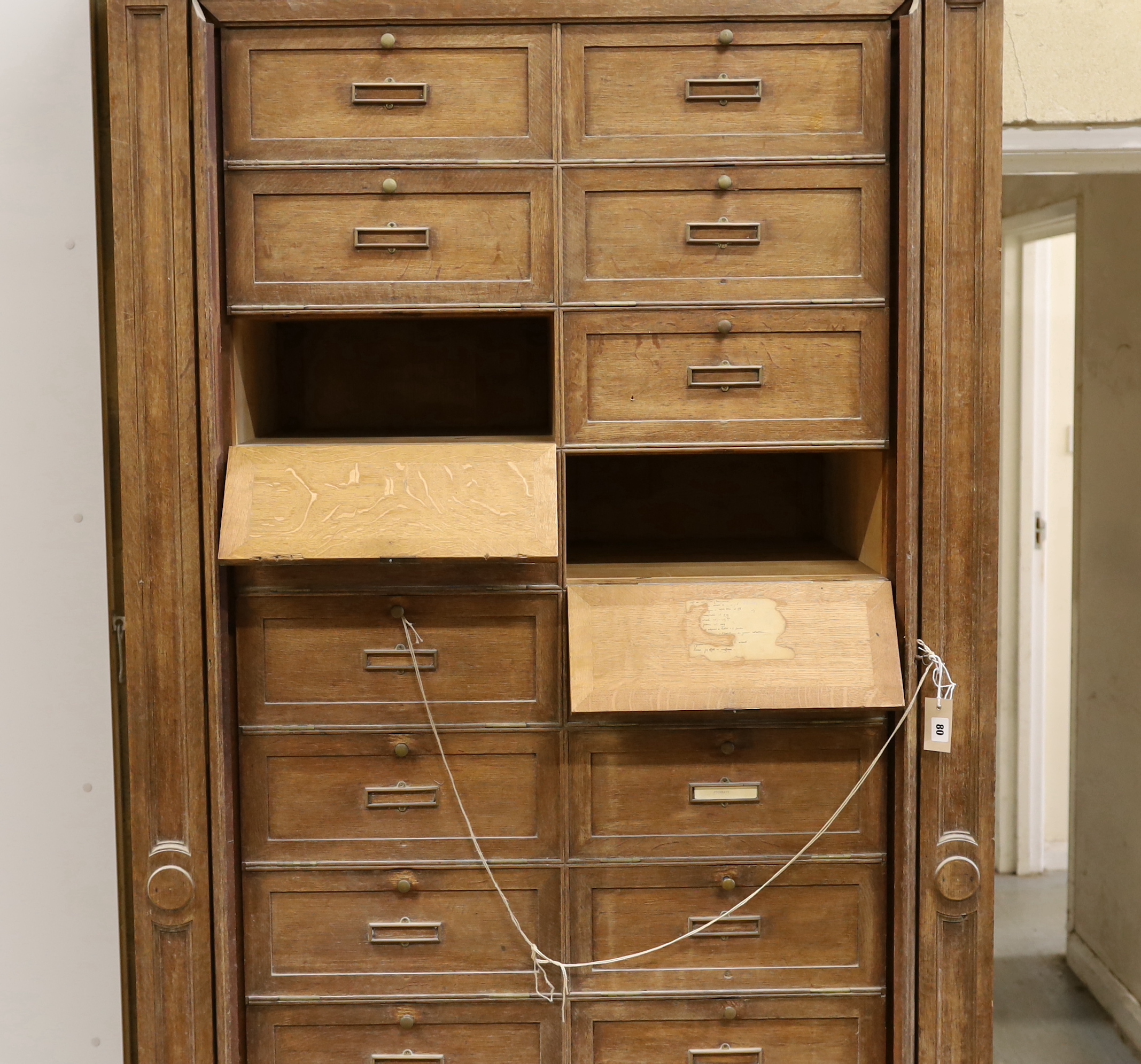 An early 20th century French oak notaries cabinet with twenty fall front compartments, width 125cm, depth 60cm, height 240cm